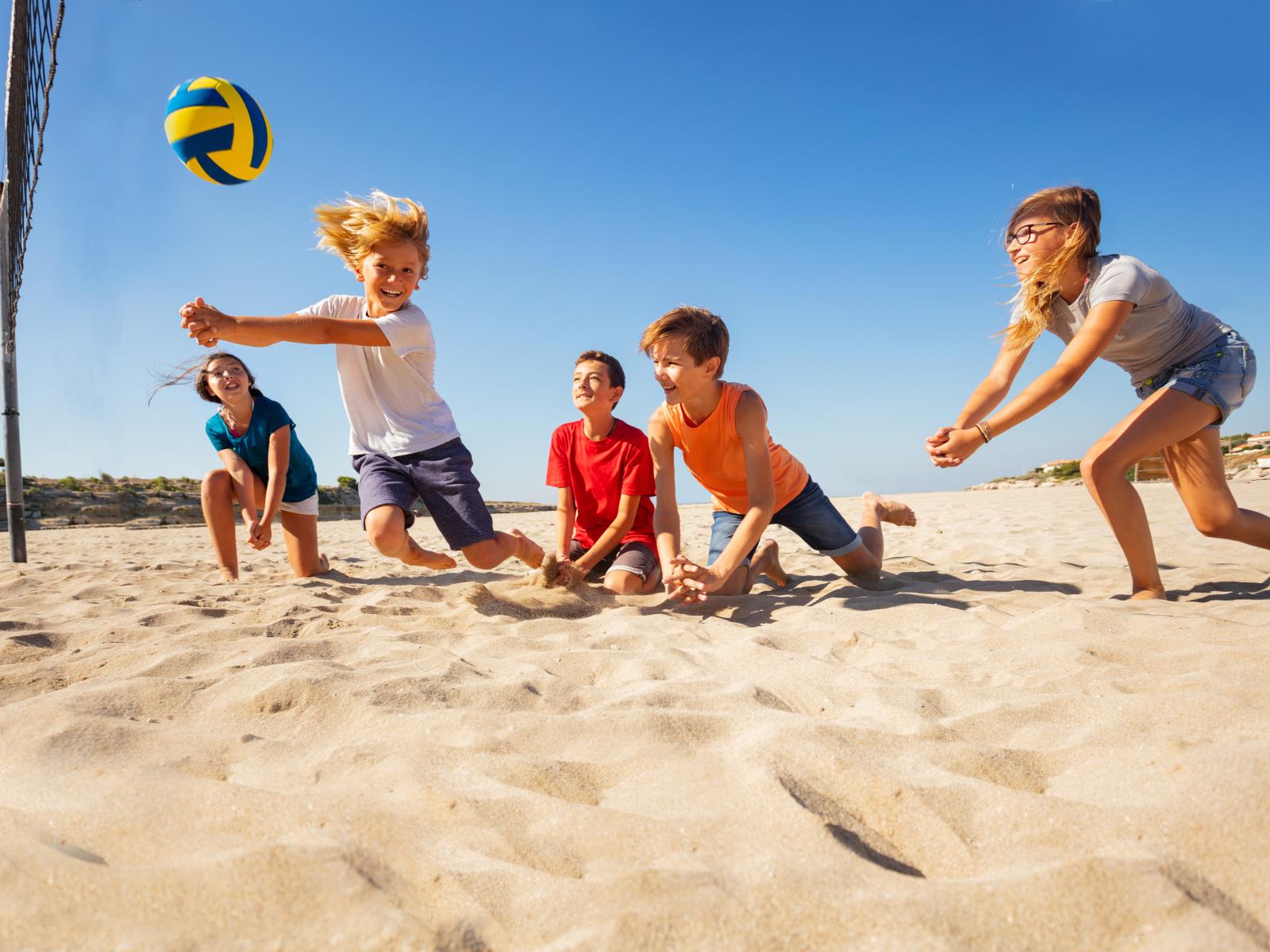 Kinder spielen Volleyball am Strand